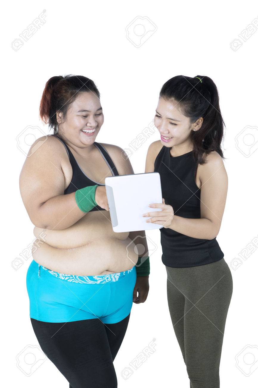太った女性は 白い背景で隔離するデジタル タブレットの何かを示す女性のトレーナー の写真素材 画像素材 Image