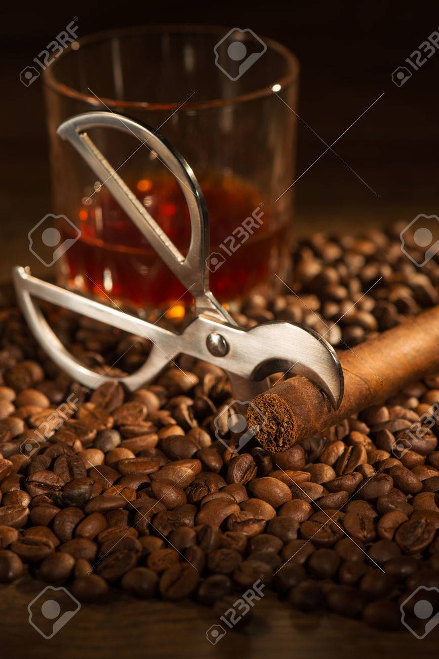 Selective Focus On The Cuban Cigar And Cutter Lying Heap Of Coffee Beans Selective Focus On The Cuban Cigar And Cutter Lying Heap Of Coffee Beans