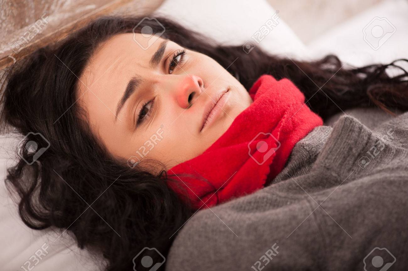 ウイルスの病気の女性 彼女の首に太いマフラーが付いているベッドで横になっていると見て動揺して赤い鼻を持つ落ち込んで若い女性のクローズ アップ画像 の写真素材 画像素材 Image