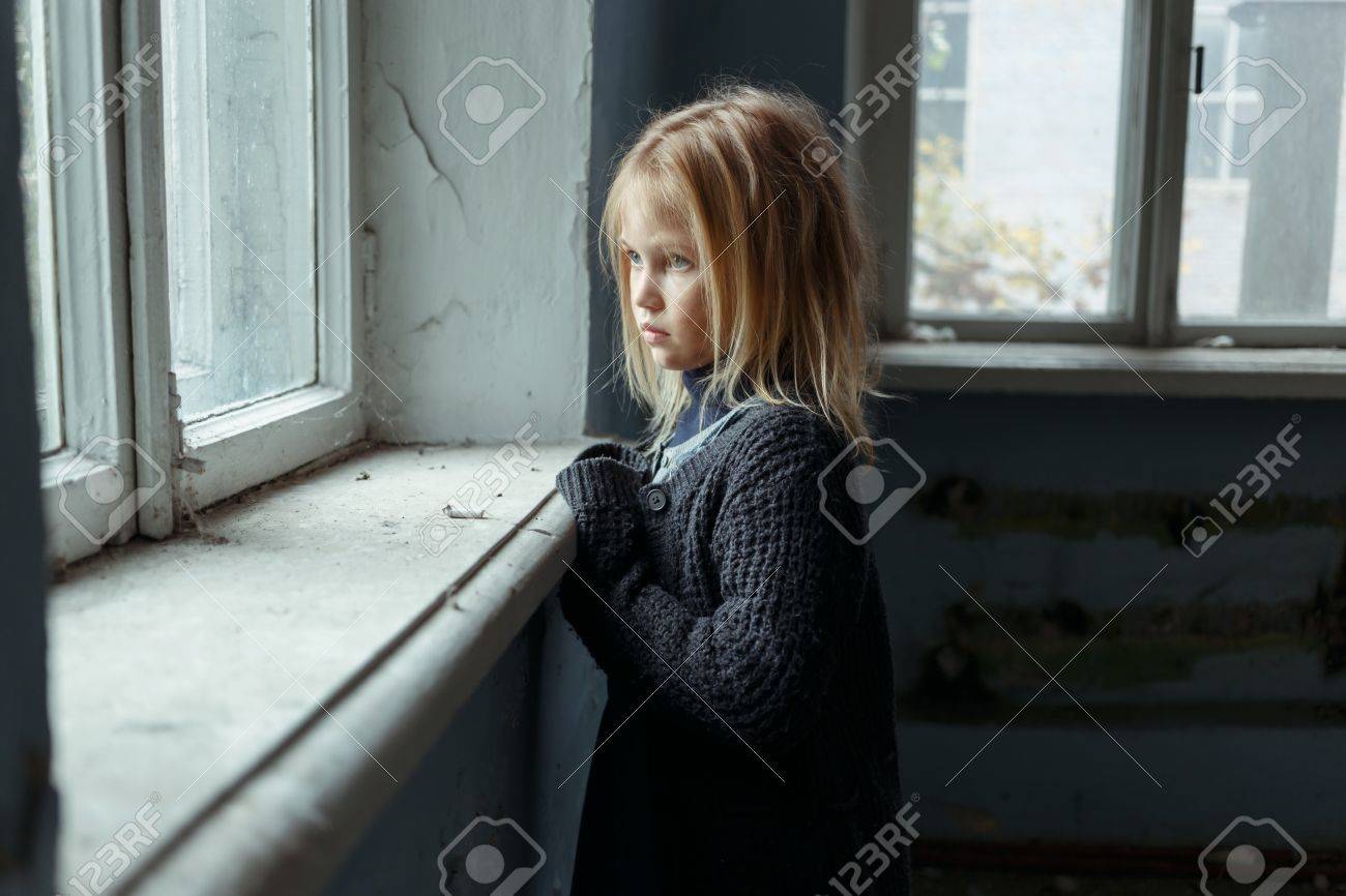 落ち込んでいる貧しい小さな女の子の窓の近くに立っていると惨めな気持ちながらよそ見のクローズ アップ の写真素材 画像素材 Image