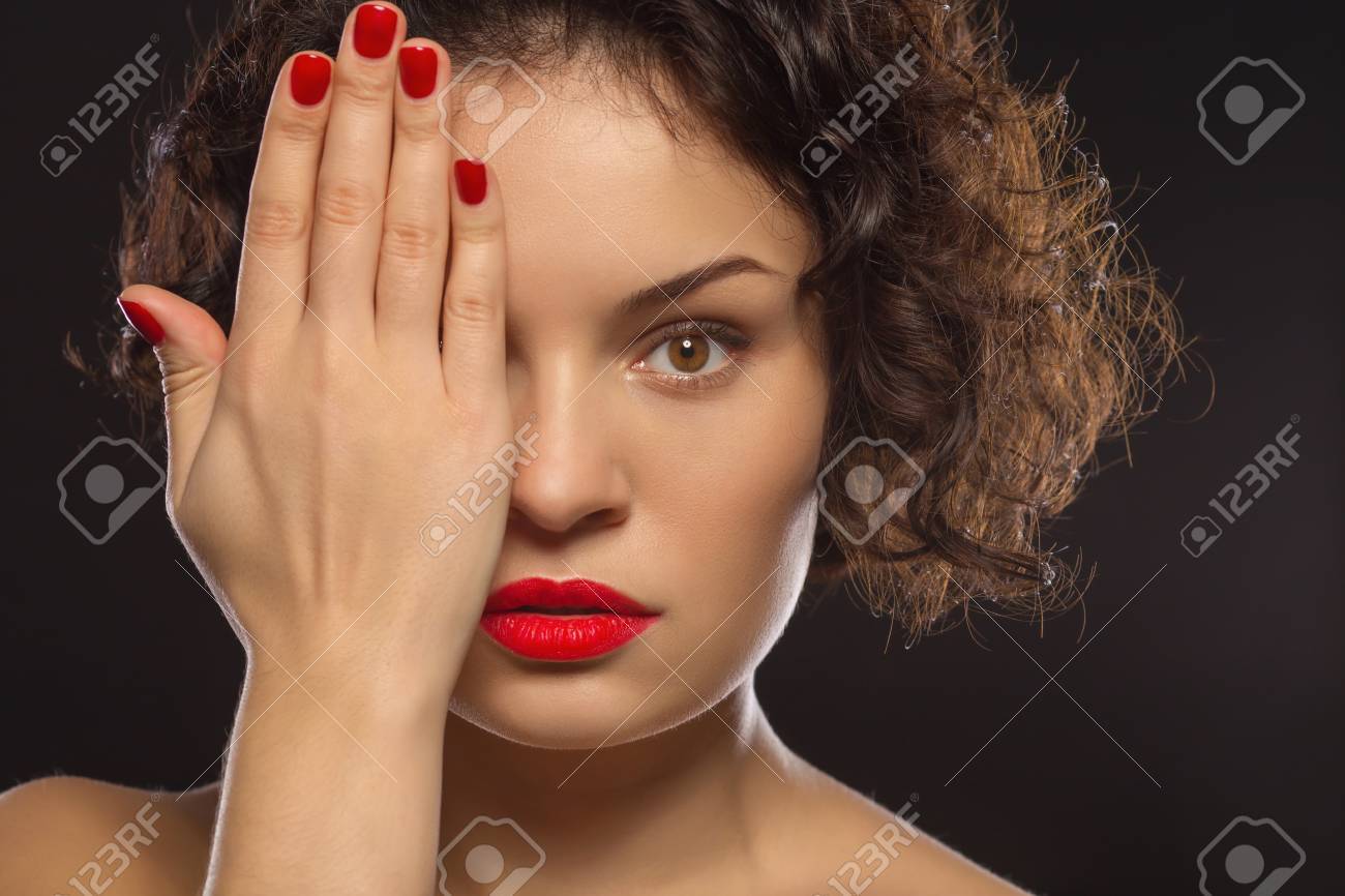 プロのポージングします 若い魅力的な女性は 彼女の顔の半分を隠すことによってカメラのポーズです の写真素材 画像素材 Image