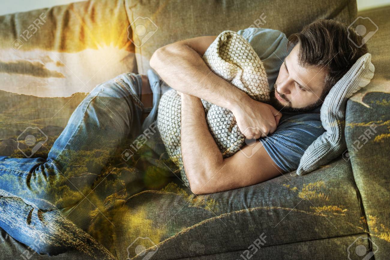 落ち込んだストレスの多い疲れ果てた男は ソファの上の部屋に横たわって 枕を抱きしめていた の写真素材 画像素材 Image
