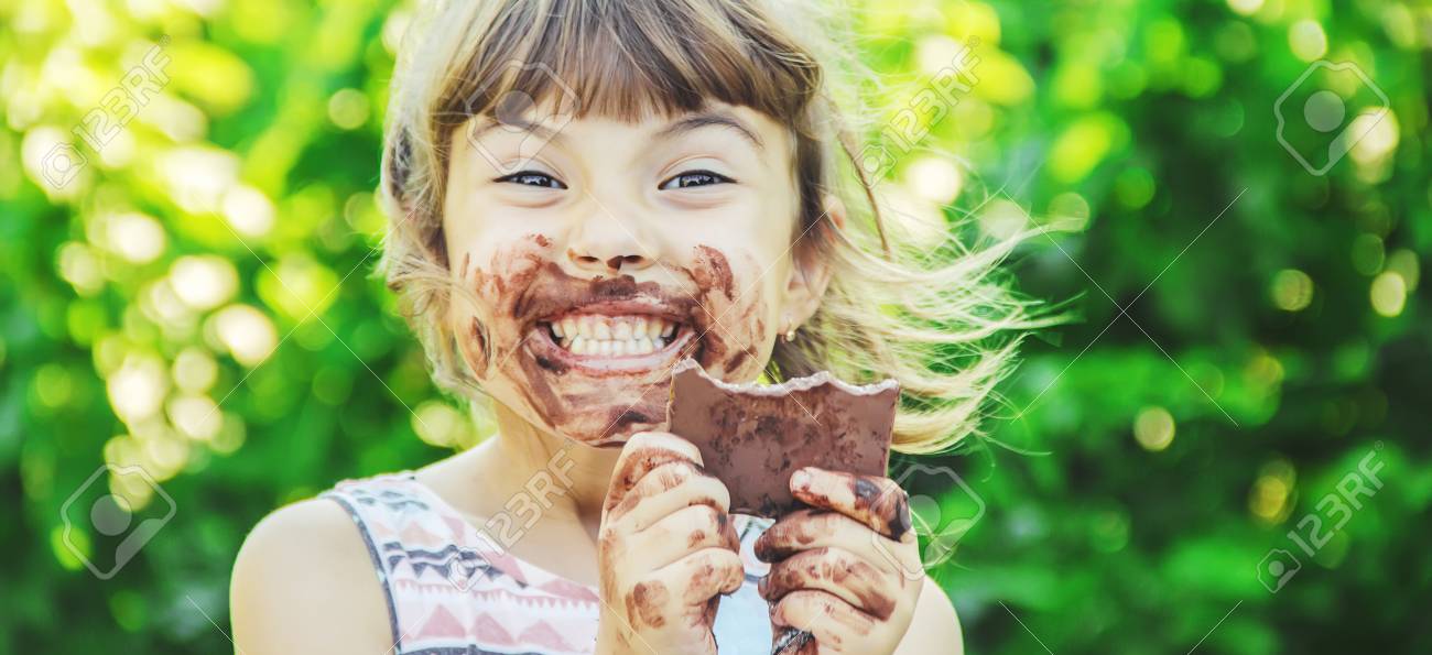 A sweet-toothed child eats chocolate. Selective focus. nature. - 121736553 A sweet-toothed child eats chocolate. Selective focus. nature. - 121736553