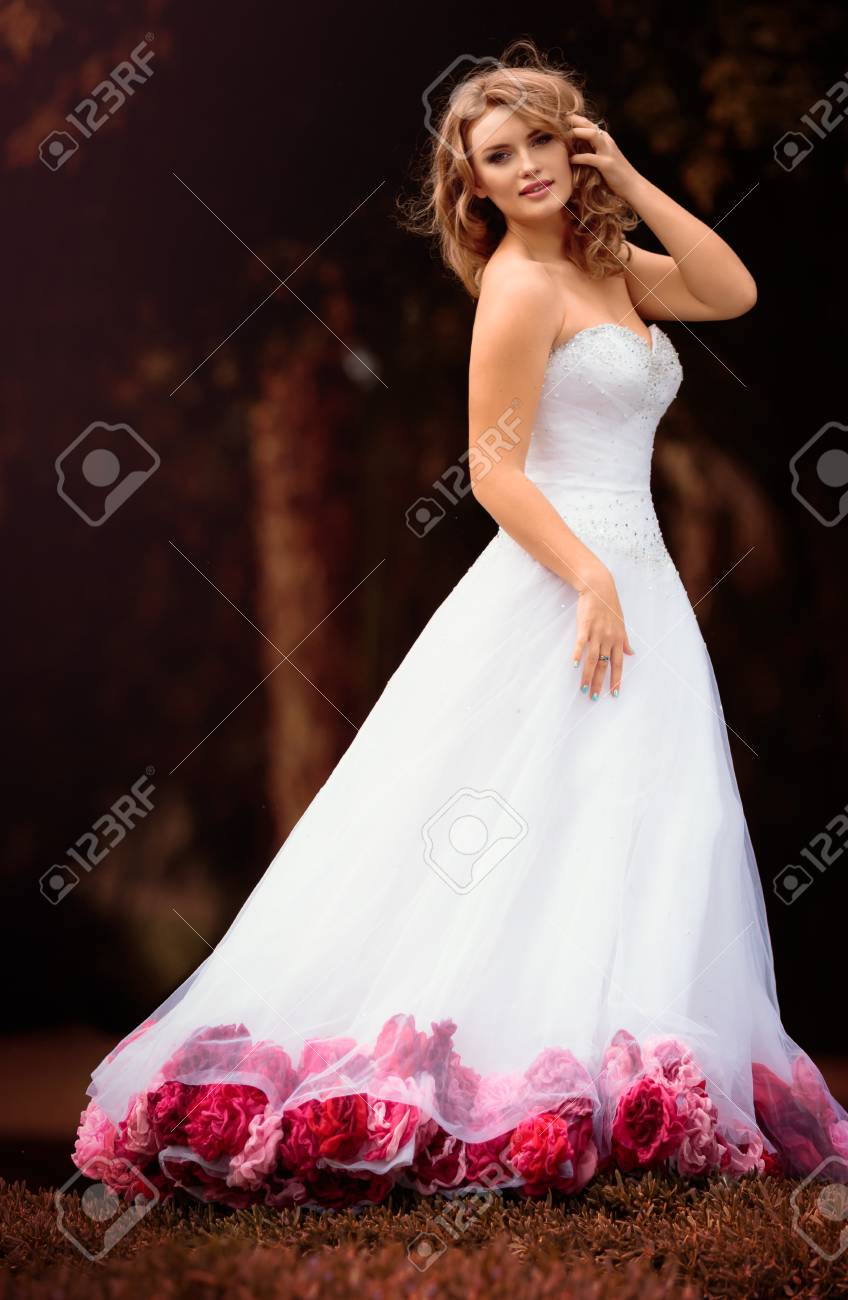 傘で白いドレスを着た金髪の美しい花嫁は美しい公園屋外結婚式のフォト セッション メモリ アルバムの赤とピンクのバラの花で装飾 結婚式の写真 の写真素材 画像素材 Image