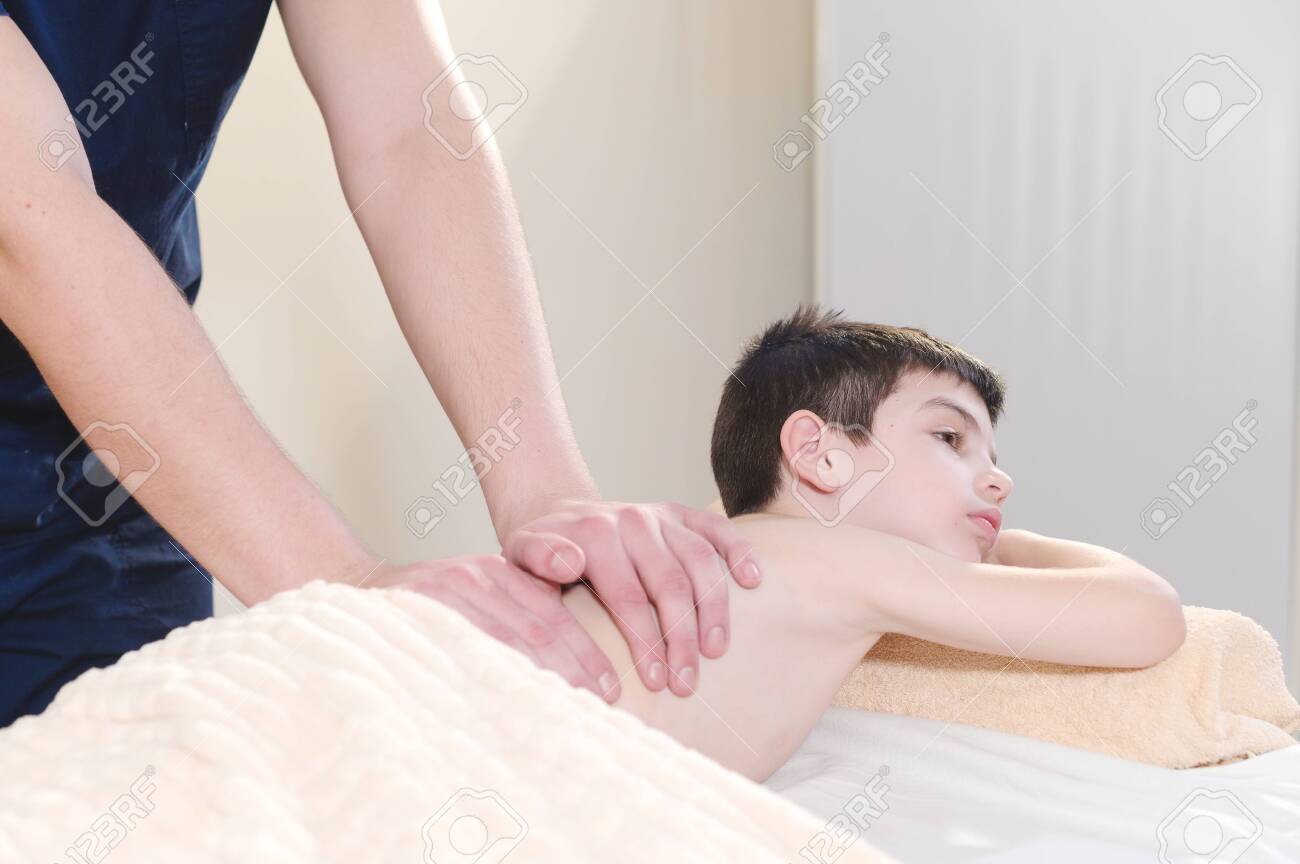 young boy massage 小さな男の子が治療マッサージからリラックスします。男性マッサージセラピストが子供の背中に医療マッサージを行いますの写真素材・画像素材 Image  118773677