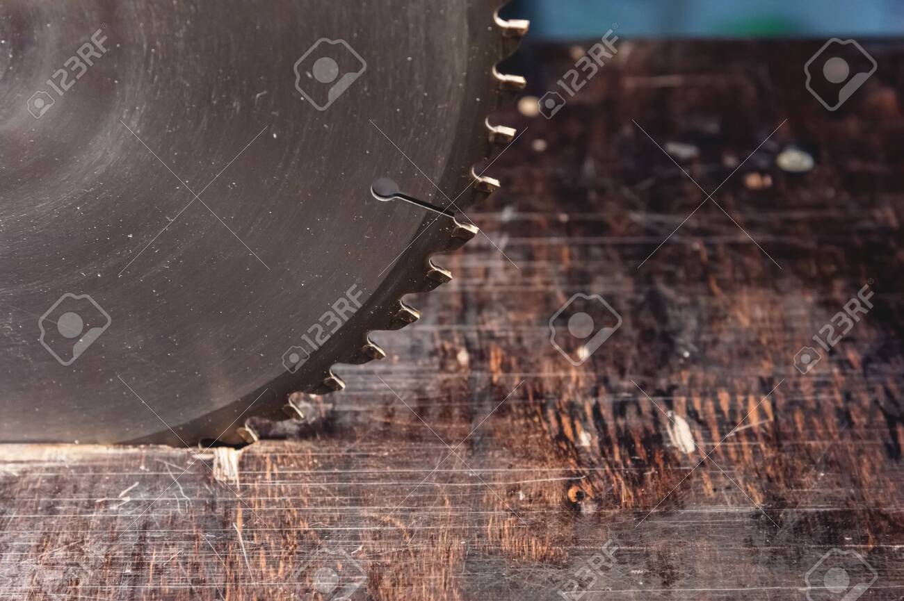 Close-up blade circular saw on the background of the wooden table. Workshop for the production of wooden products. Joiners cutting tool - 121012483 Close-up blade circular saw on the background of the wooden table. Workshop for the production of wooden products. Joiners cutting tool - 121012483