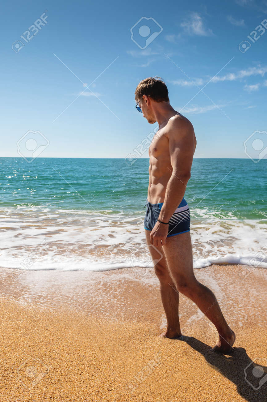 Young Man, Naked, Of An Athletic Build Stands On A Sandy Beach By The Sea  Stock Photo, Picture and Royalty Free Image. Image 167843077.