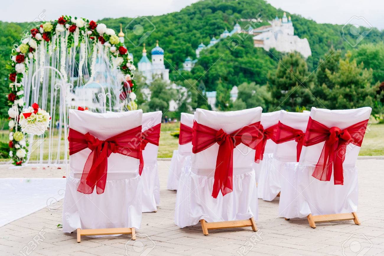 屋外の美しい結婚式 赤いリボンの装飾が施された椅子 結婚式のアーチは 緑の自然な背景の山に布と白と黄色の花で作られています 豪華なスタイル の写真素材 画像素材 Image