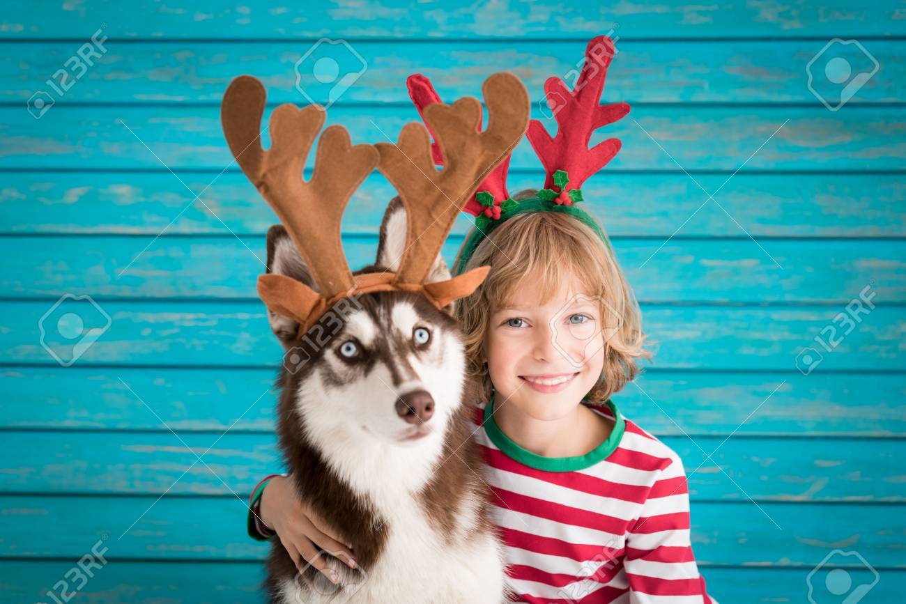 Happy child and dog on Christmas eve. Kid and pet dressed in Santa hat. - 87820904 Happy child and dog on Christmas eve. Kid and pet dressed in Santa hat. - 87820904