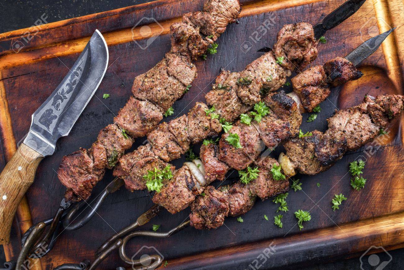 Grilling marinated shashlik on a grill. Shashlik is a form of Shish kebab  popular in Eastern, Central Europe and other places. Shashlyk meaning skewer  Stock Photo - Alamy