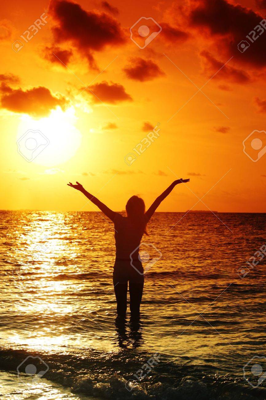 happy woman standing on a sunset in ocean waves - 11975139 happy woman standing on a sunset in ocean waves - 11975139