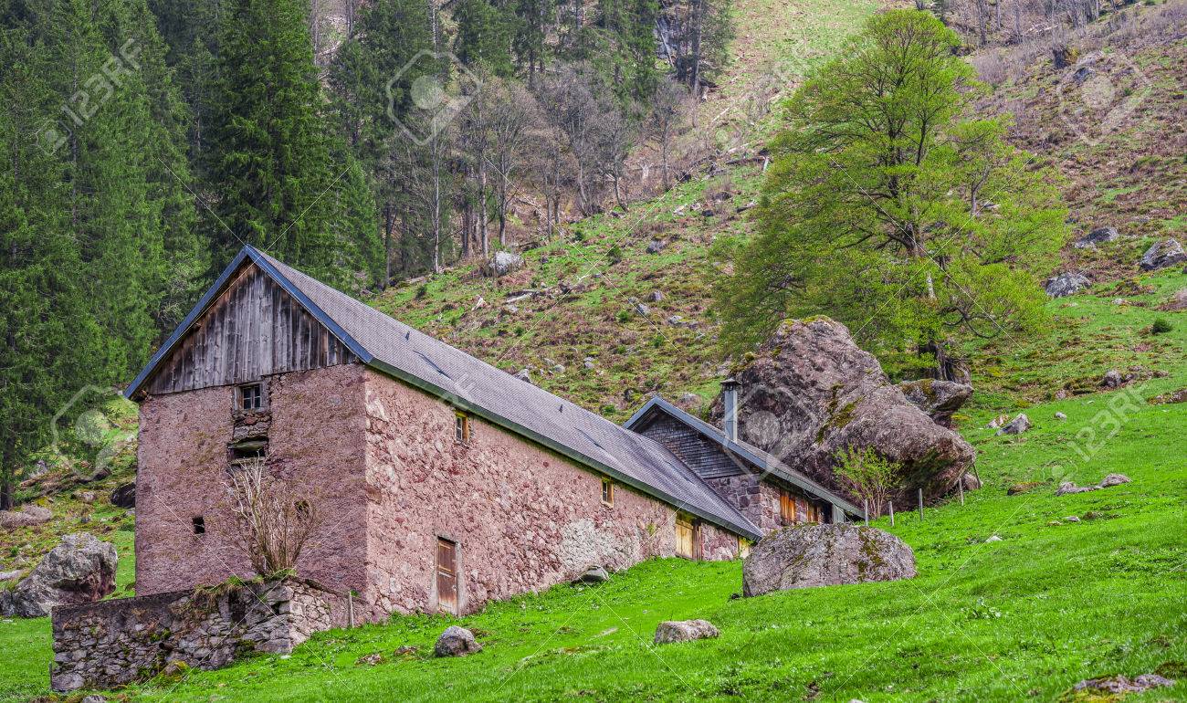 従来の壁石の安定とハウス スイスの伝統的な安定と落ちた山の巨大な岩に囲まれた石の壁と鉄片屋根で構築された家 の写真素材 画像素材 Image