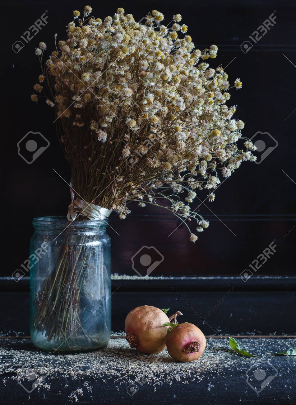 Un Bouquet De Fleurs Séchées Se Trouvent Sur Le Piano à Côté Du Fruit De Grenade