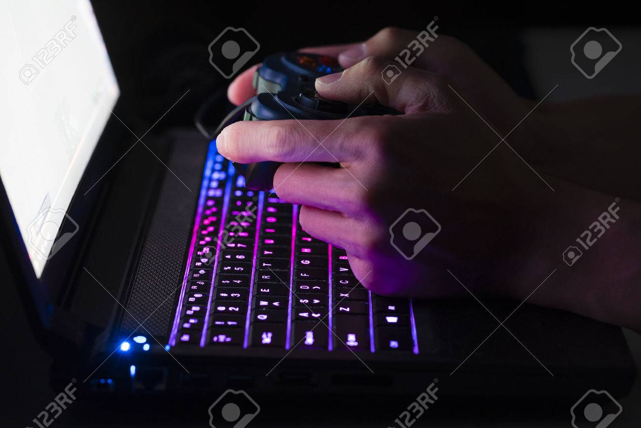 Playing computer game on laptop with joypad - 54430038 Playing computer game on laptop with joypad - 54430038