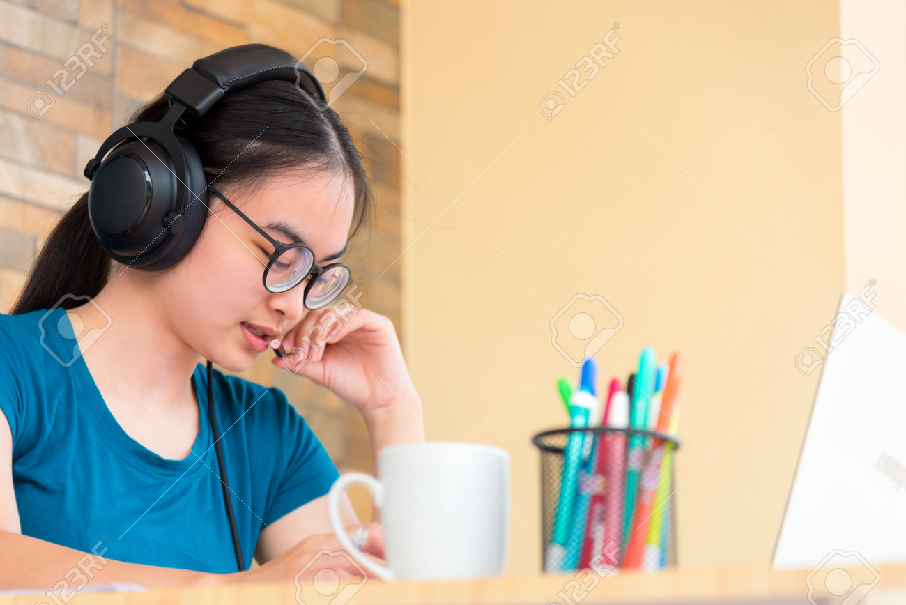 Linda garota asiática usando fone de ouvido aprendendo música de