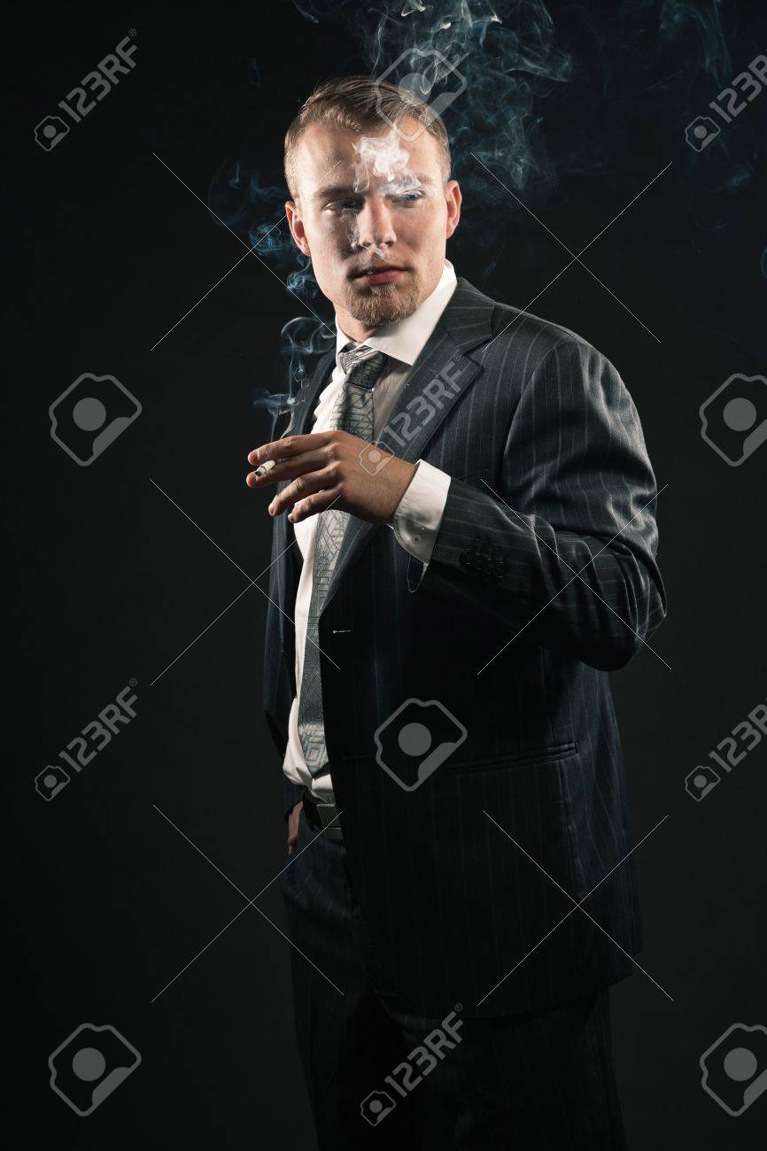 ファッション スーツ喫煙タバコの男。ブラックに対して撮影スタジオ