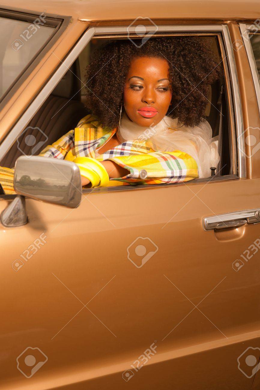 レトロな 70 年代ファッションのアフリカ系アメリカ人女性が金の 70 年代に運転車 の写真素材 画像素材 Image