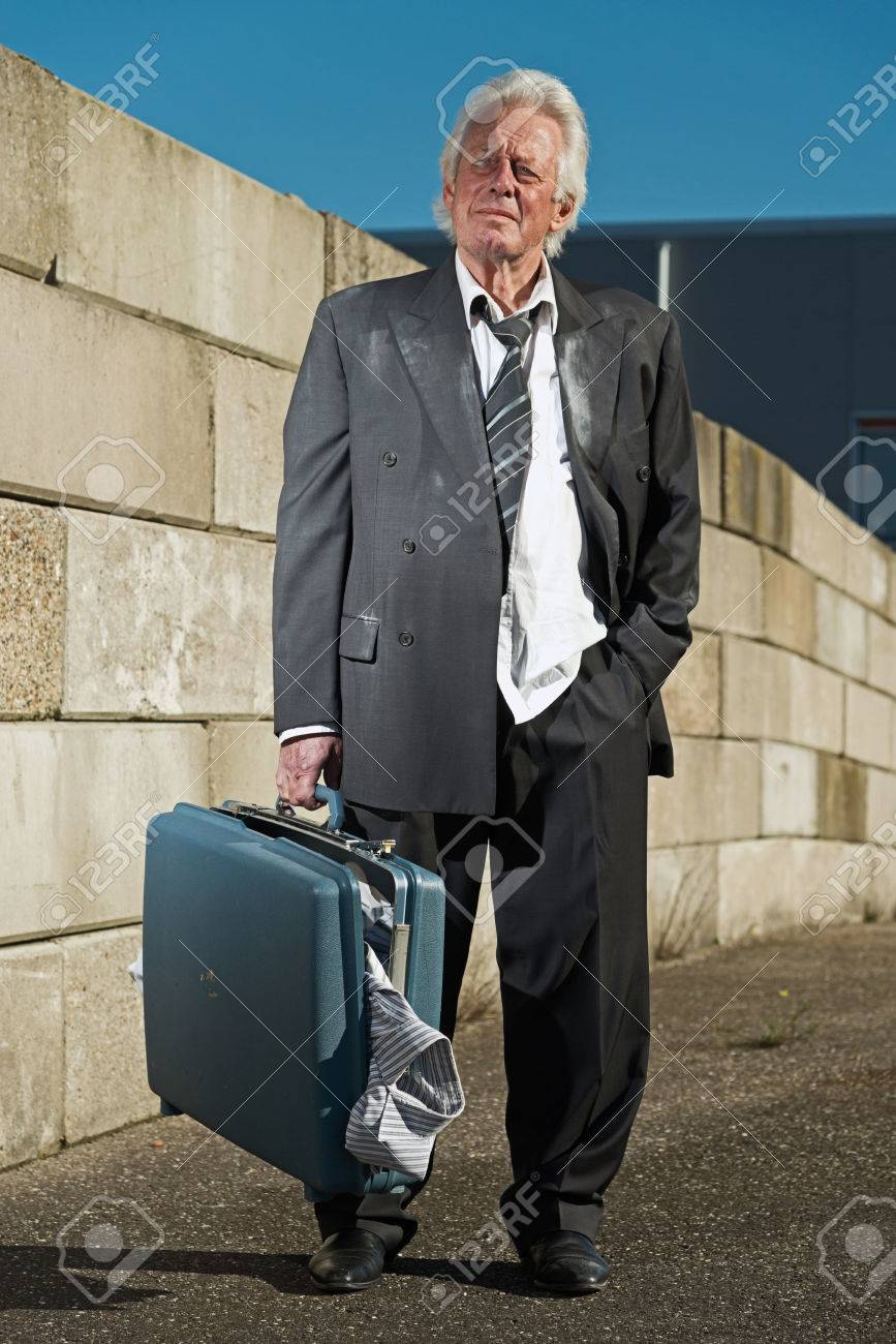 23183291-depressed-senior-business-man-without-a-job-and-homeless-on-the-street-holding-a-suitcase-wearing-a-.jpg