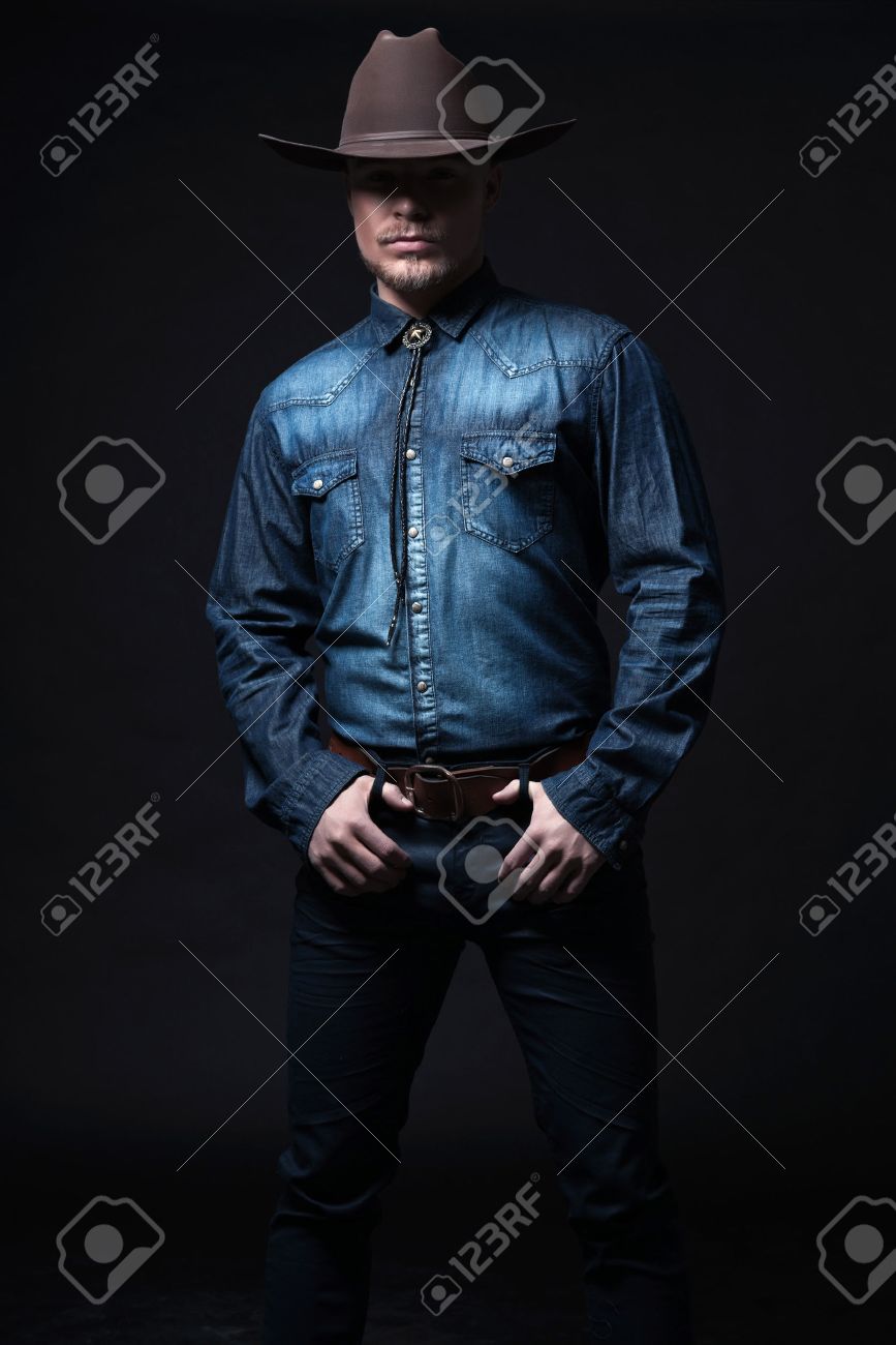 現代ファッション カウボーイ 茶色の帽子とシャツ ブルー ジーンズを着用します ブロンドの髪とひげ スタジオ ショット黒に対して の写真素材 画像素材 Image