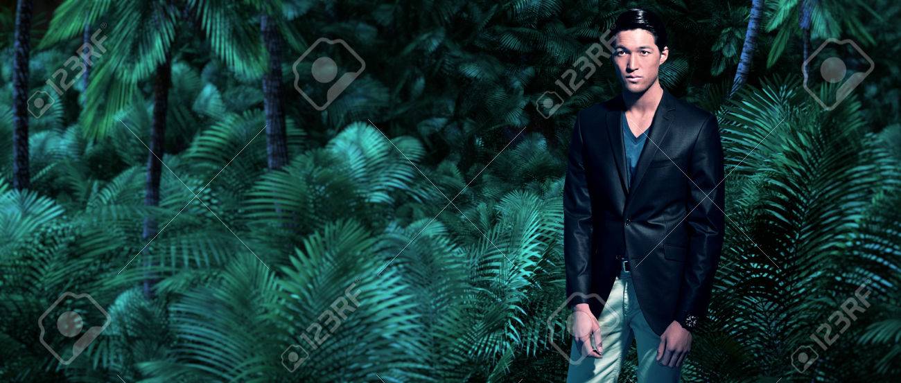 Mode Homme Daffaires Asiatique Dans La Jungle De Fougères Vertes Et Des Palmiers Portant Le Costume Gris Foncé Et Chemise Bleue