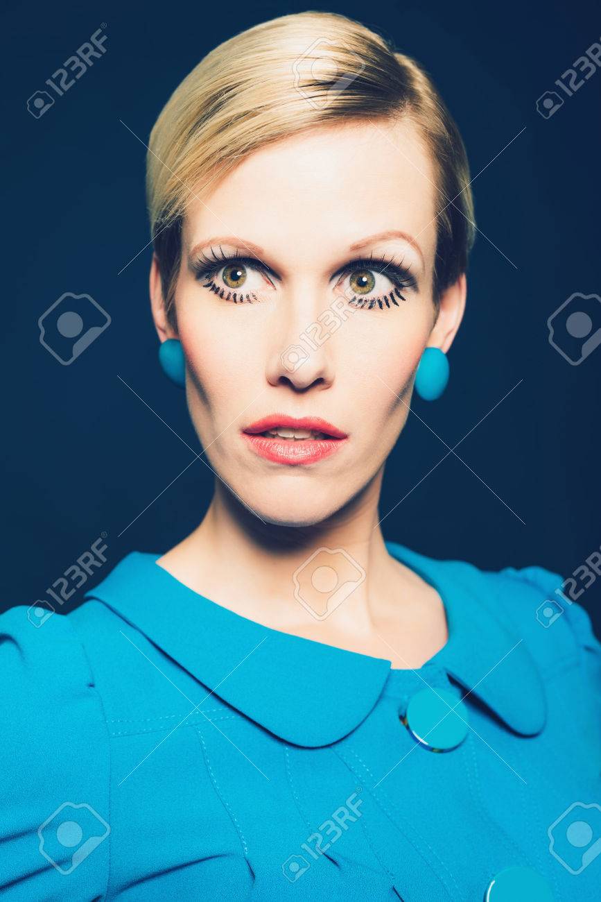 妖精の顔とスタイリッシュなブルーのドレス イヤリングを身に着けている真剣な表情で深刻な成熟した金髪の女性 の写真素材 画像素材 Image