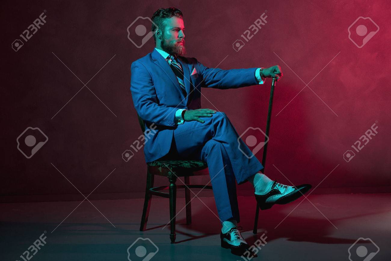 ステッキまたは杖大気赤い照明 サイドビューで椅子にフォーマルなスーツで座っているとエレガントな紳士 の写真素材 画像素材 Image
