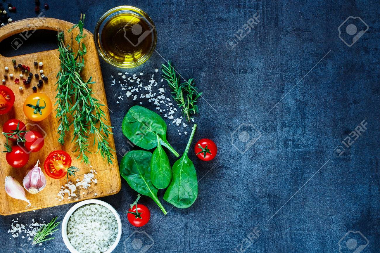 Organic vegetarian ingredients, olive oil and seasoning on rustic wooden cutting board over dark vintage background with space for text, top view. - 54733183 Organic vegetarian ingredients, olive oil and seasoning on rustic wooden cutting board over dark vintage background with space for text, top view. - 54733183