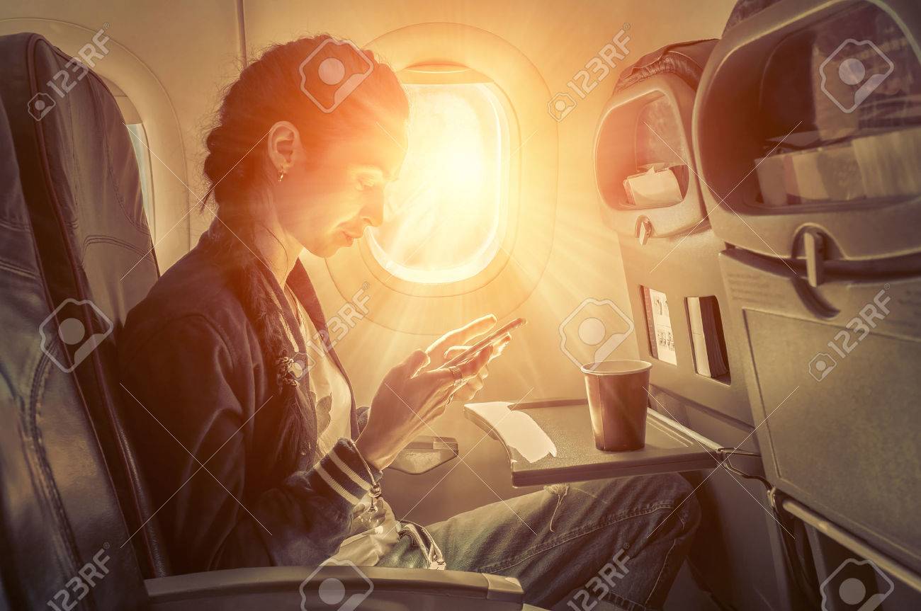 Woman sitting at airplane and looking to mobil phone. - 50687913 Woman sitting at airplane and looking to mobil phone. - 50687913