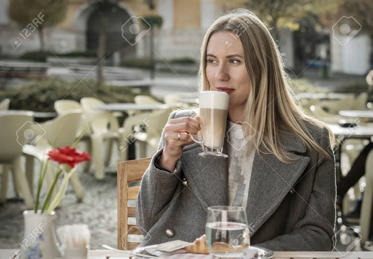 カフェ カフェ晴れた秋の日で太陽光の下で遅いとマグカップを手に持っての美しい若い女性の女の子 の写真素材 画像素材 Image