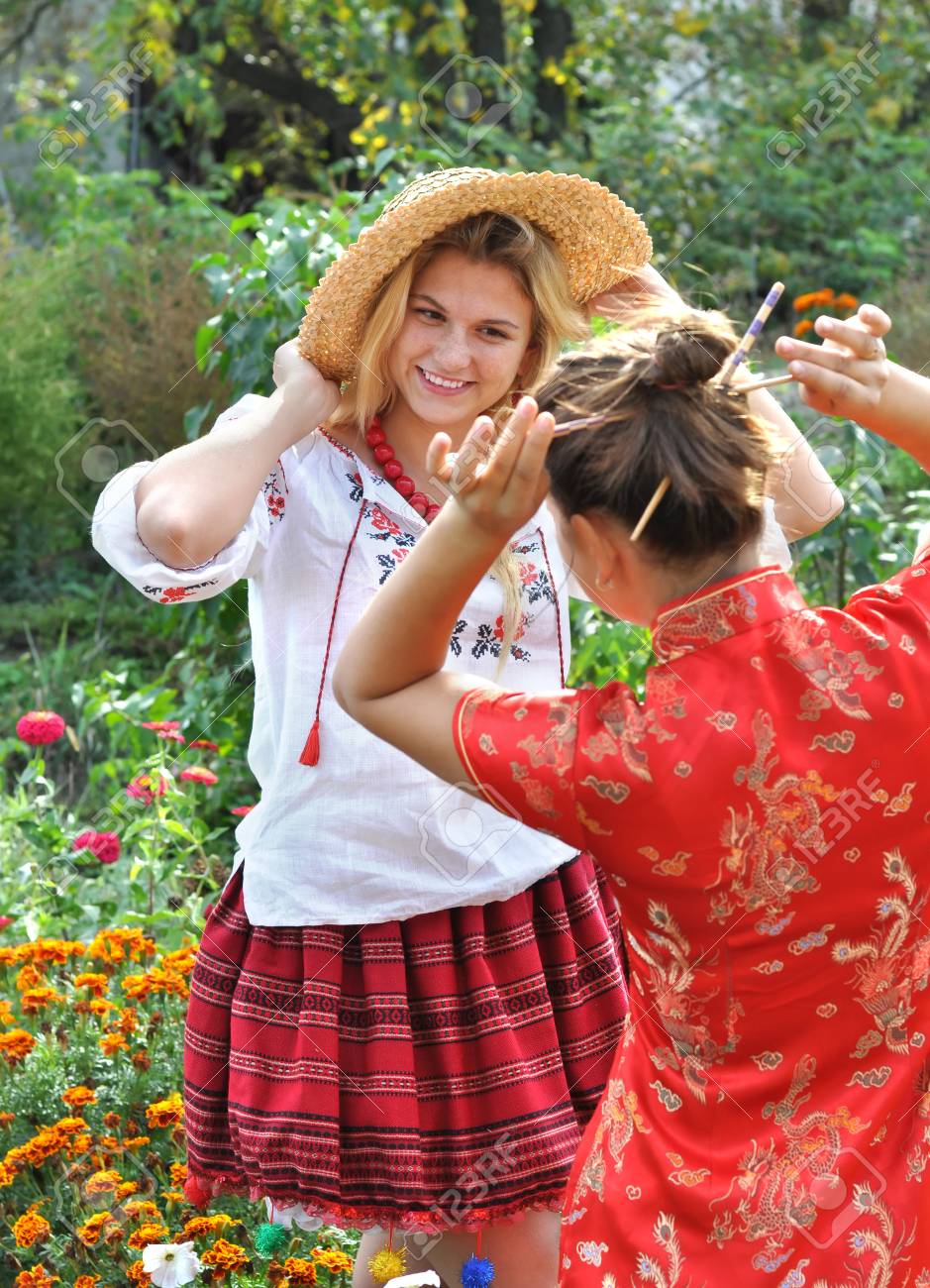 two teenage girls in traditional ukrainian and chinese clothes