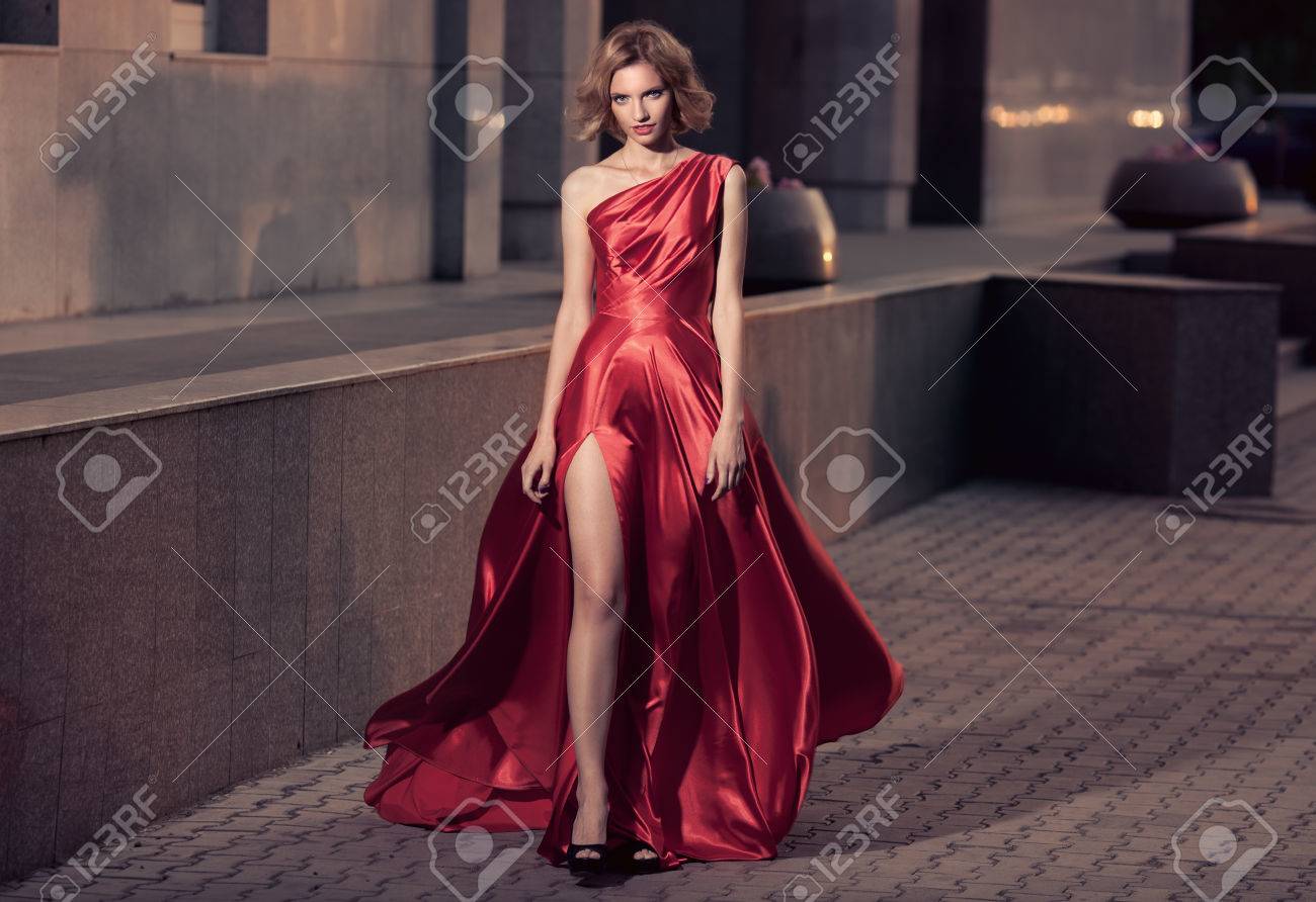 Young Beautiful Woman In Fluttering Red Dress. City Background. - 34745953 Young Beautiful Woman In Fluttering Red Dress. City Background. - 34745953