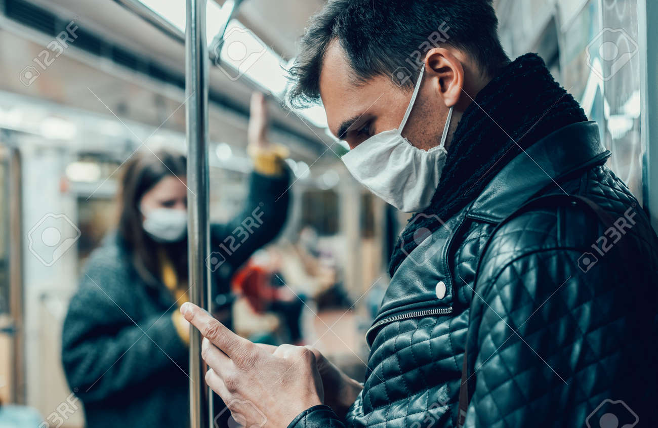 passenger in a protective mask reading a message on his smartphone. - 159464439 passenger in a protective mask reading a message on his smartphone. - 159464439