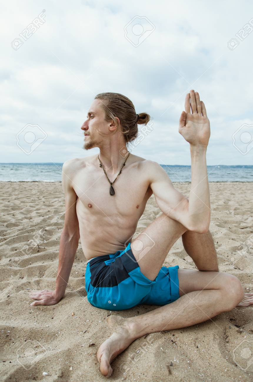 若い細い男は砂浜のビーチでヨガします アルダ Matsiendrasana の写真素材 画像素材 Image