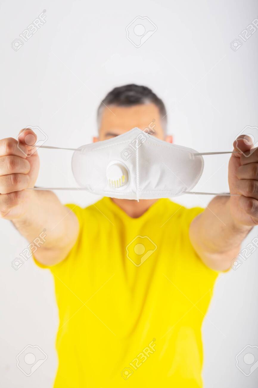 Download A Man In Yellow T Shirt Holds Medical Mask Coronavirus Concept Stock Photo Picture And Royalty Free Image Image 144875745 PSD Mockup Templates