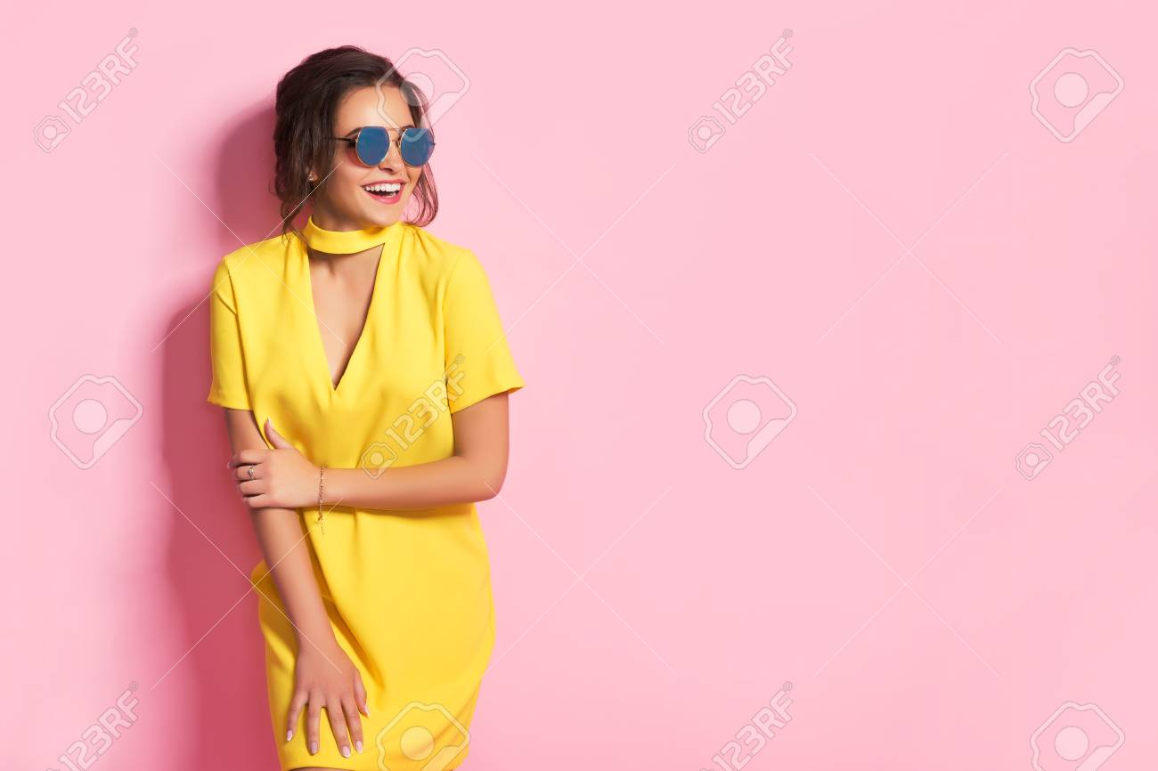 Beautiful girl in colorful clothes wearing sunglasses posing on pink background in studio. - 78750097 Beautiful girl in colorful clothes wearing sunglasses posing on pink background in studio. - 78750097