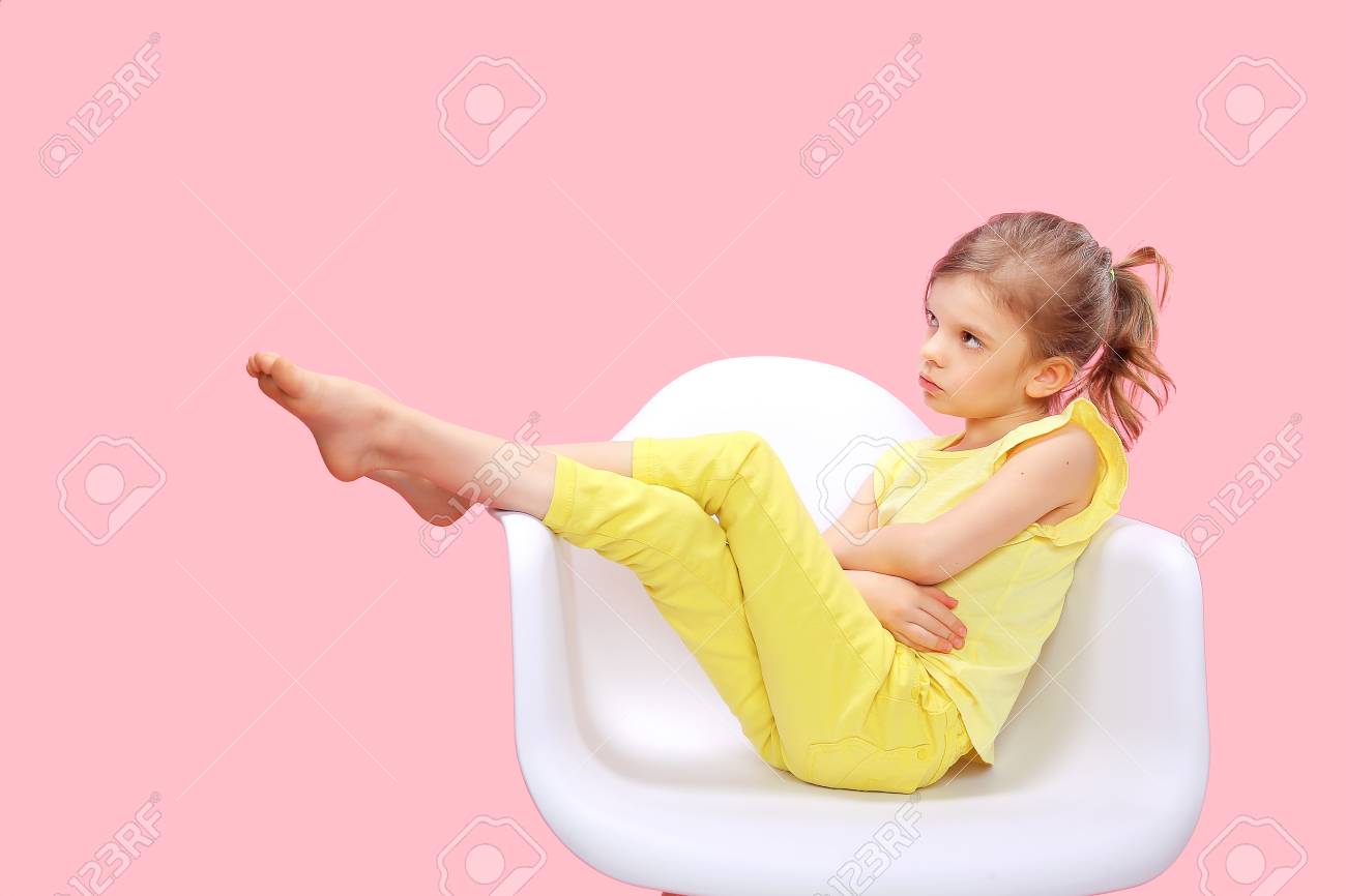 Dreaming Stylish little girl in yellow clothes sitting and posing in chair on pink background. - 100397961 Dreaming Stylish little girl in yellow clothes sitting and posing in chair on pink background. - 100397961