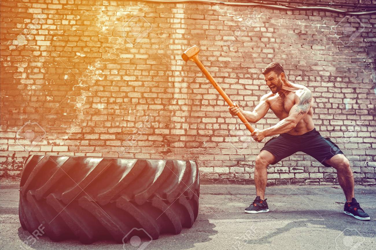 Sport Fitness Man Hitting Wheel Tire With Hammer Sledge Crossfit Training, Young Healthy Guy Gym Interior OUTSIDE - 105789203 Sport Fitness Man Hitting Wheel Tire With Hammer Sledge Crossfit Training, Young Healthy Guy Gym Interior OUTSIDE - 105789203