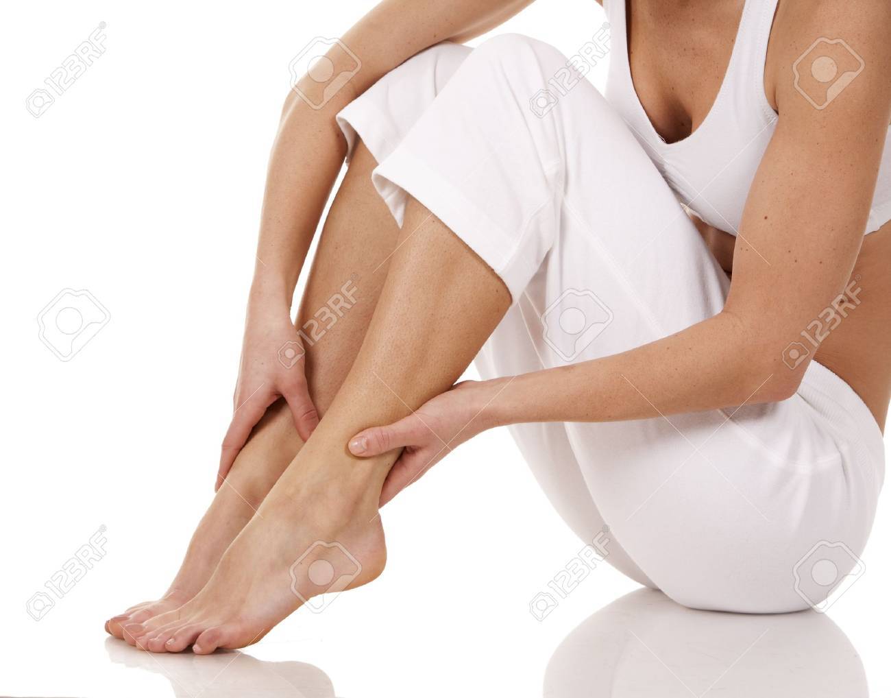 brunette holding her feet on white isolated background - 18688232 brunette holding her feet on white isolated background - 18688232