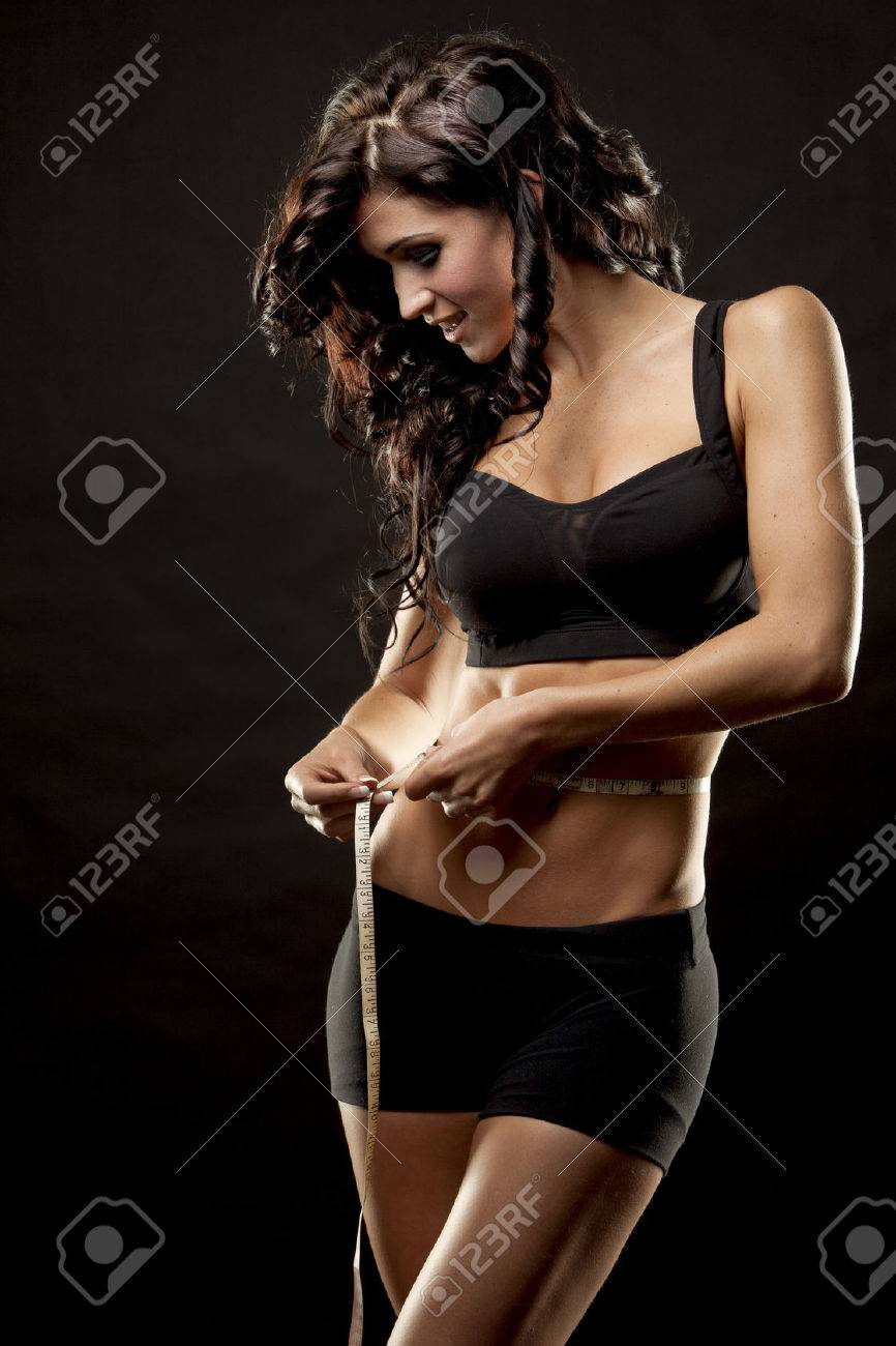 fitness model is measuring her waist on black background - 23219857 fitness model is measuring her waist on black background - 23219857