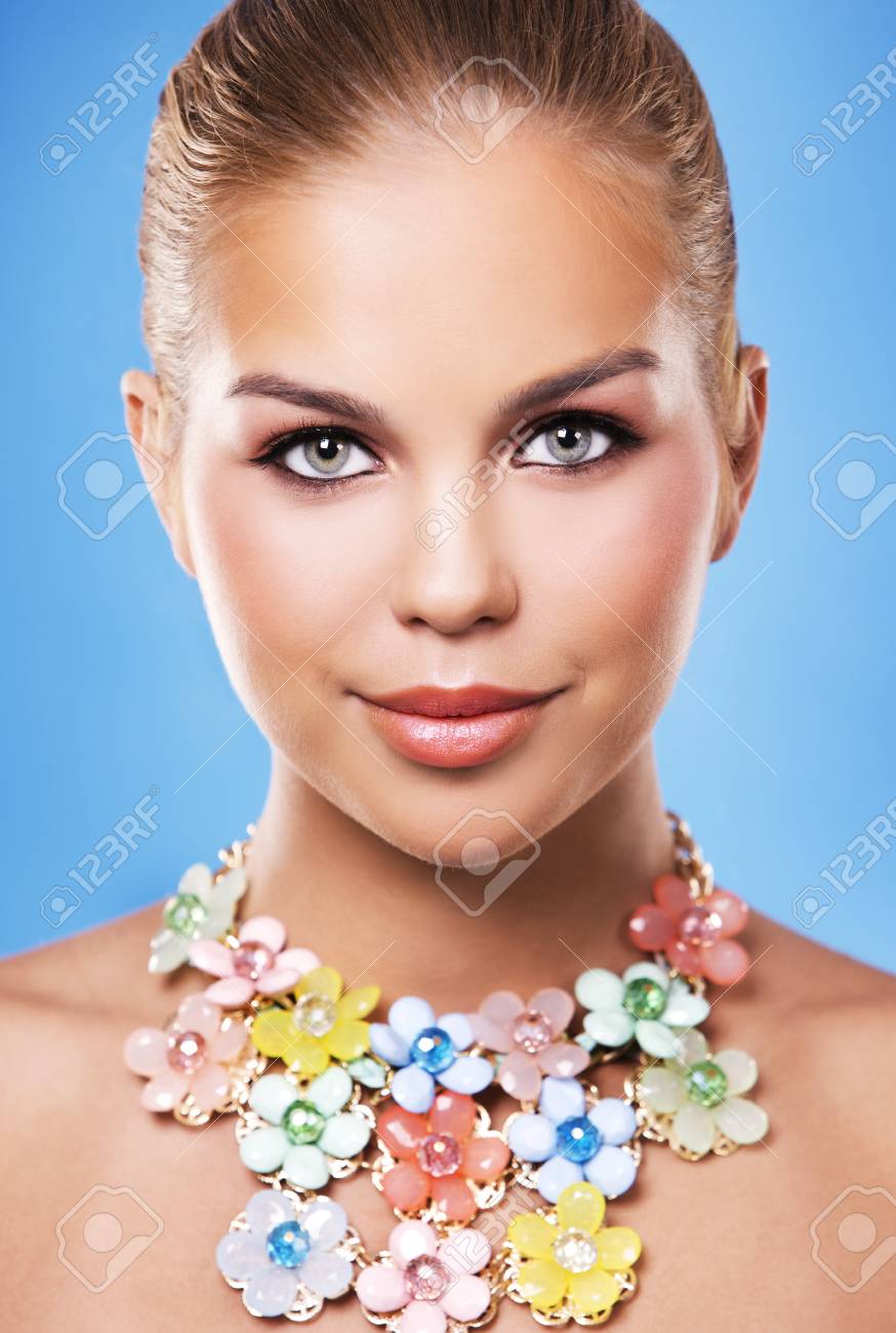 Belle Femme Avec Maquillage Foncé Et Rouge à Lèvres Posant Sur Fond Bleu Portant Collier Fleur Bijoux Printemps Et En été