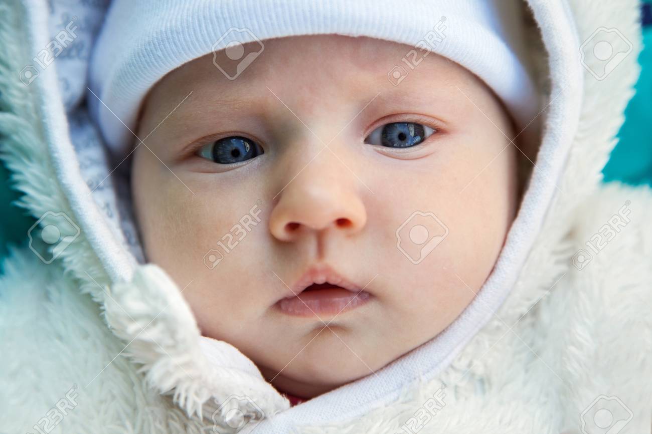 Close Up Cute Babys Face With Big Blue Eyes In A White Hat And