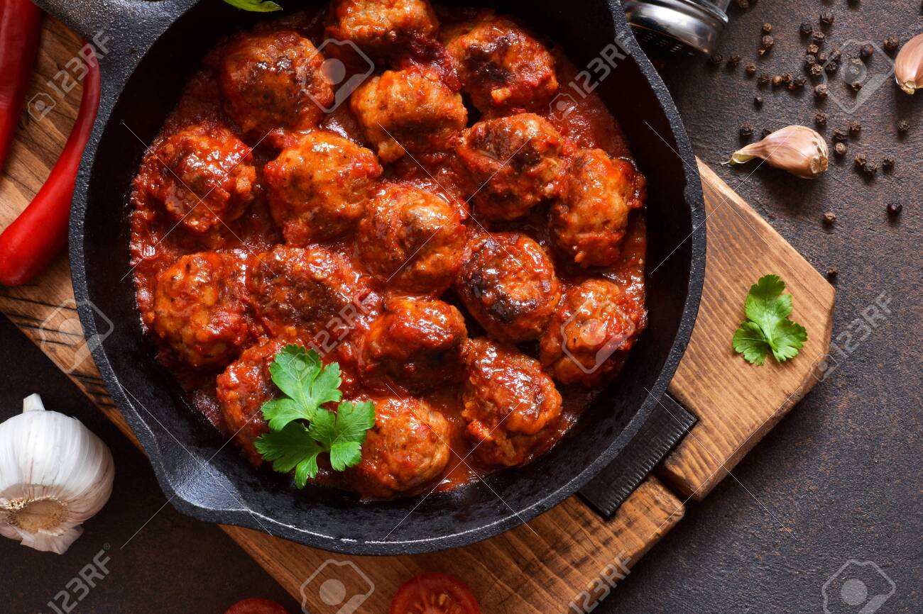 Meatballs in sweet and sour tomato sauce on the kitchen table. Top view - 120125030 Meatballs in sweet and sour tomato sauce on the kitchen table. Top view - 120125030