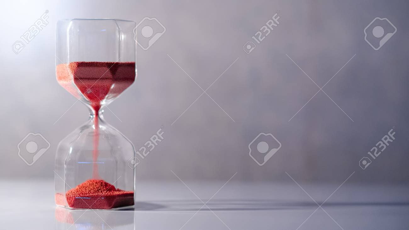 Red sand running through the shape of modern hourglass on white table.Time passing and running out of time. Urgency countdown timer for business deadline concept with copy space - 107254409 Red sand running through the shape of modern hourglass on white table.Time passing and running out of time. Urgency countdown timer for business deadline concept with copy space - 107254409