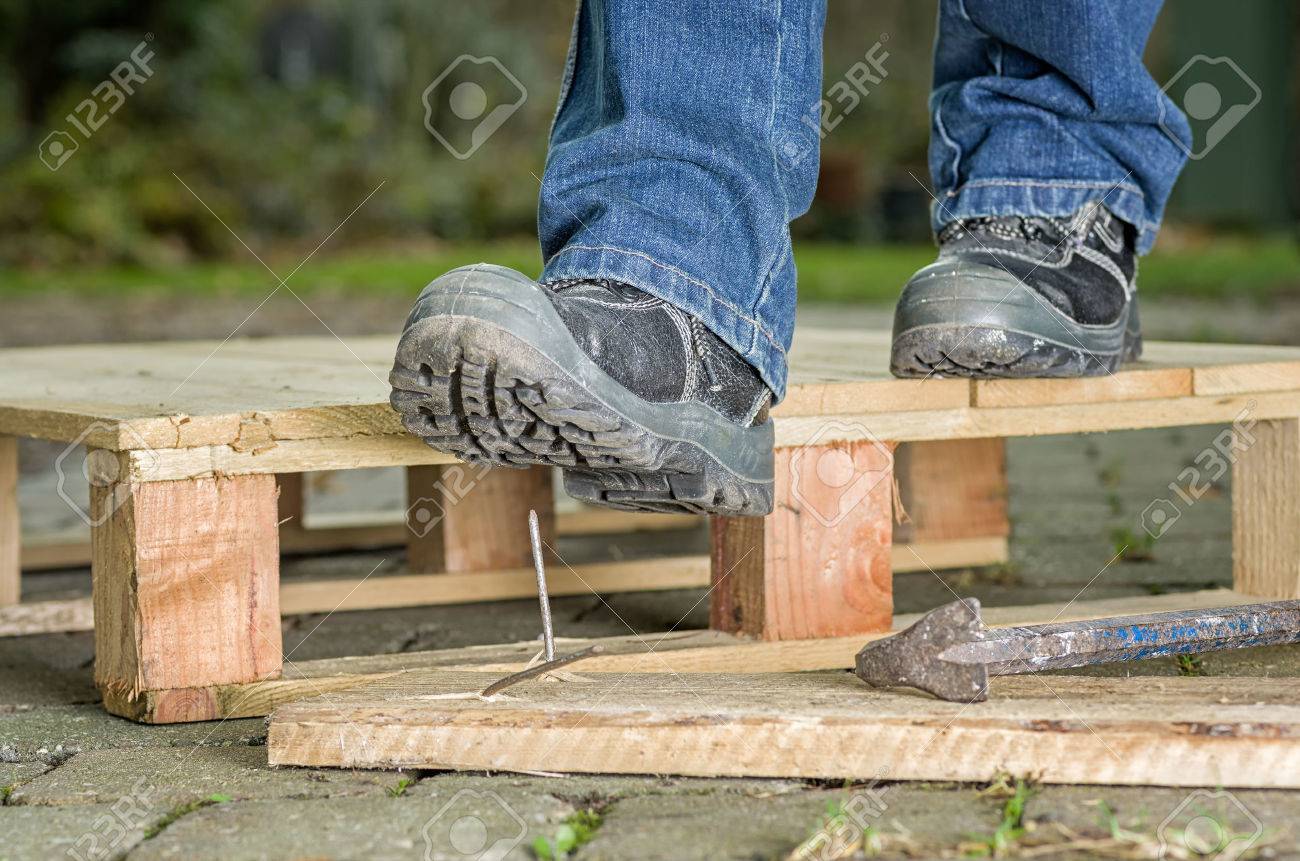 Ouvrier Avec Des Chaussures De Sécurité Marche Sur Un Clou Banque