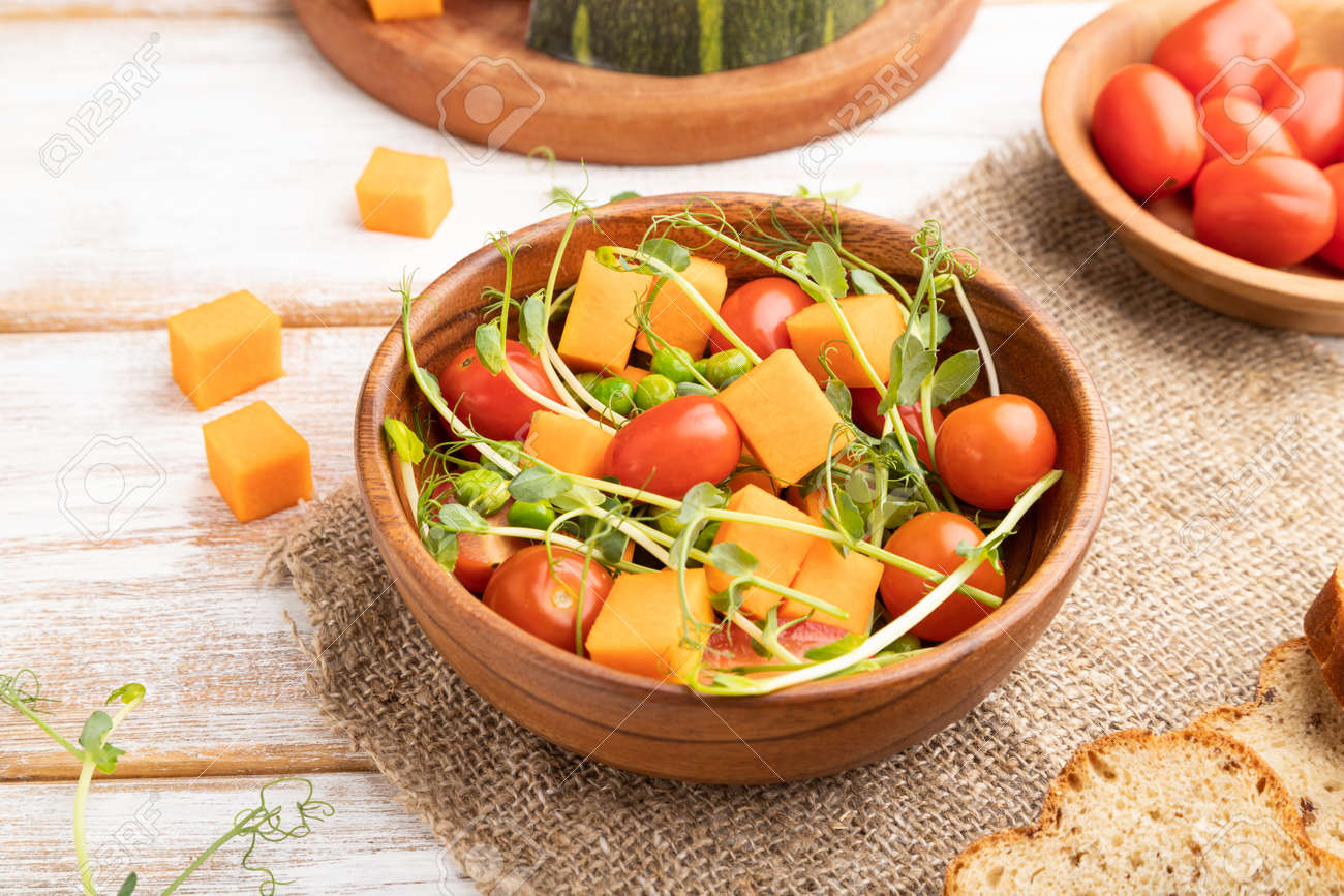 Vegetarian vegetable salad of tomatoes, pumpkin, microgreen pea sprouts on white wooden background and linen textile. Side view, close up. - 169839460 Vegetarian vegetable salad of tomatoes, pumpkin, microgreen pea sprouts on white wooden background and linen textile. Side view, close up. - 169839460