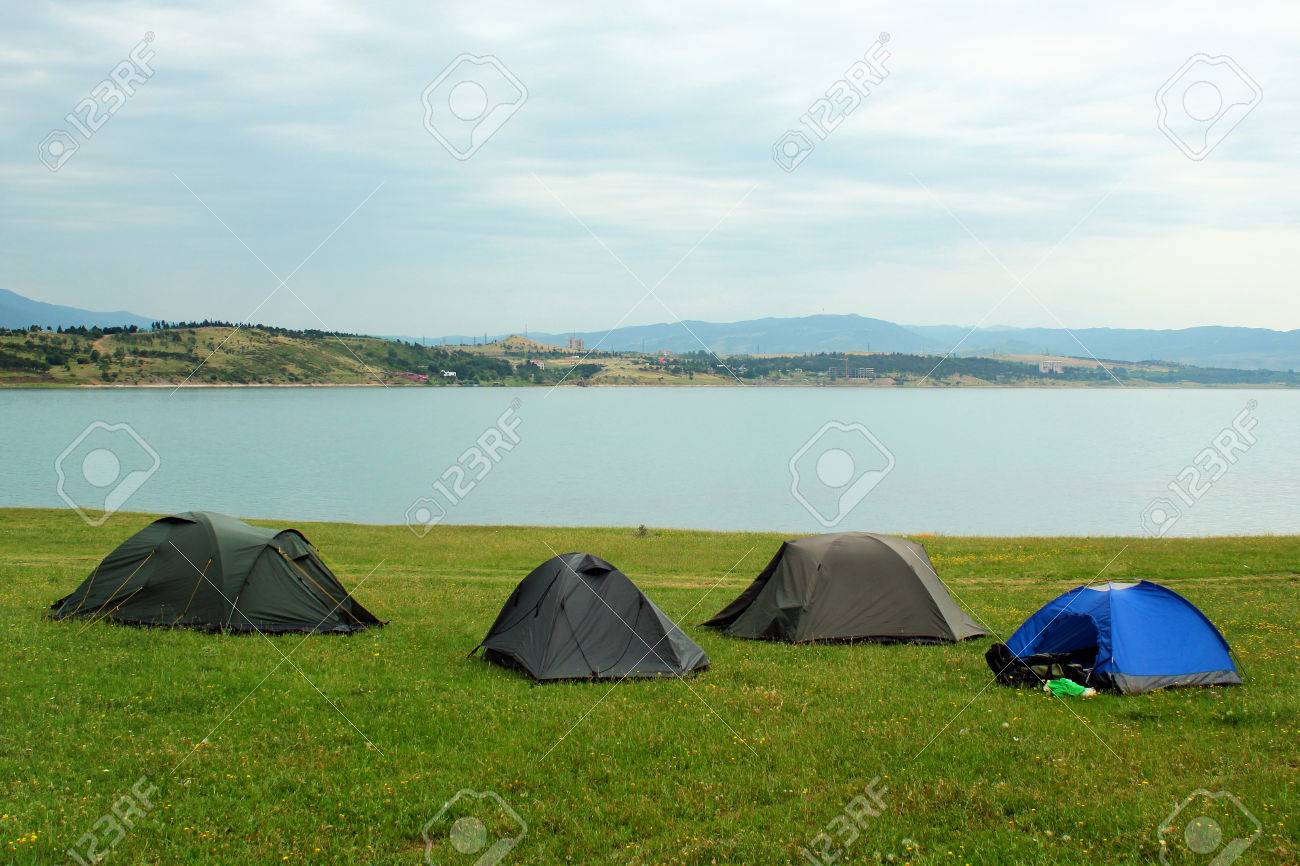 Zelte Auf Dem Campingplatz In Der Nähe Des Wasserreservoir Camping Zelten auf grünen Wiesen neben Meer beleuchtet von