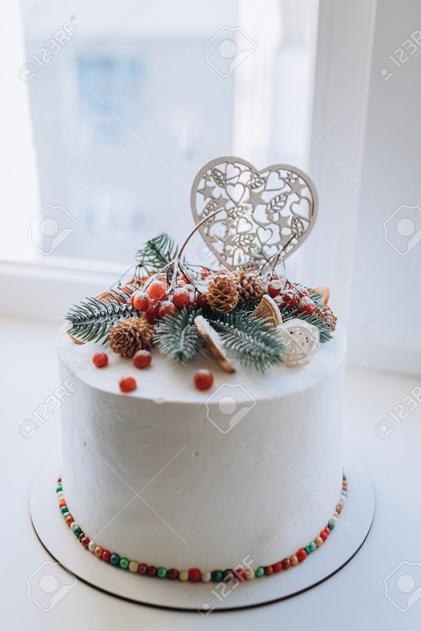 チョコレートコインで覆われた白いホリデーホワイトケーキ 雪玉とトウヒの木の枝、松ぼっくり、木のハート ケーキの上の番号2021は赤い果実で出されます  新年のコンセプトの写真素材・画像素材 Image 196310108