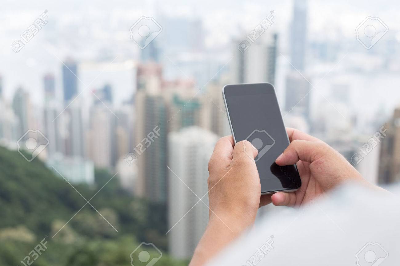 hand holding mobile phone with cityscape as background - 42370559 hand holding mobile phone with cityscape as background - 42370559
