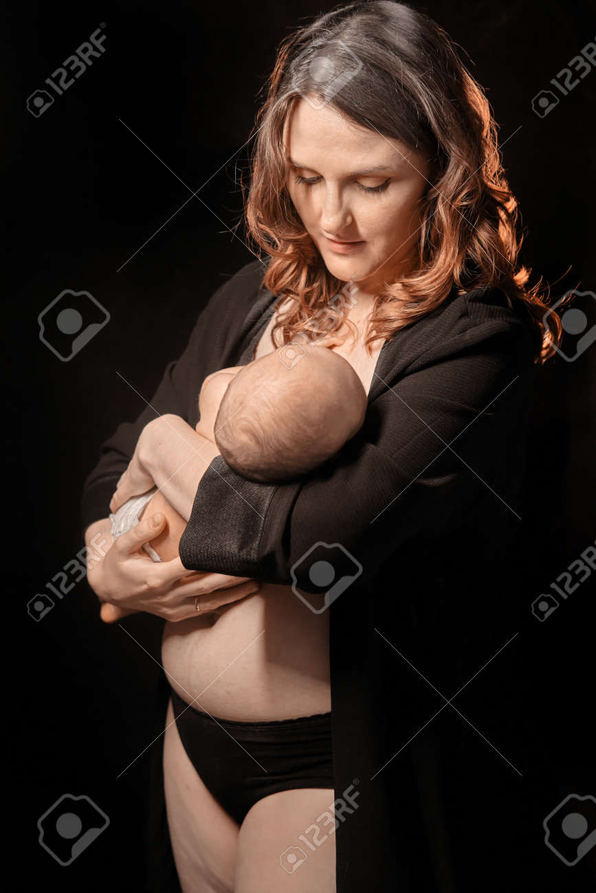 Happy Woman Mother Holds A Sleping Newborn Baby Boy In Her Arms, Black  Studio Background. Mom Smiles With A Child In Her Hands Stock Photo,  Picture and Royalty Free Image. Image 172741901.