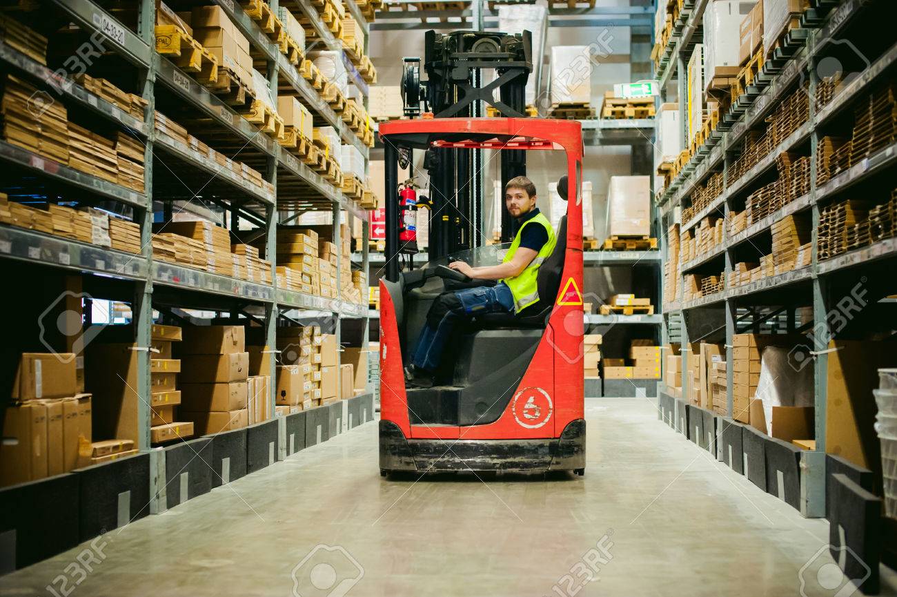 young man in working clothes, driver Reachtruck busy working on the logistics warehouse store - 68934263 young man in working clothes, driver Reachtruck busy working on the logistics warehouse store - 68934263